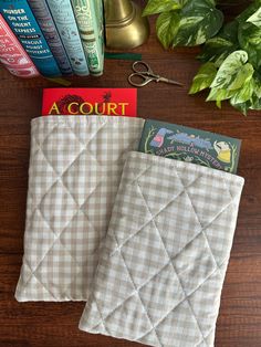 two books are sitting next to each other on a table with some plants in the background