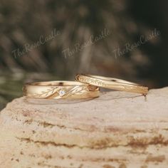 two wedding rings sitting on top of a rock