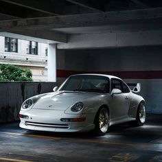 a white porsche parked in a parking garage