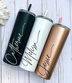 three personalized tumblers sitting next to each other on a white wooden table with flowers