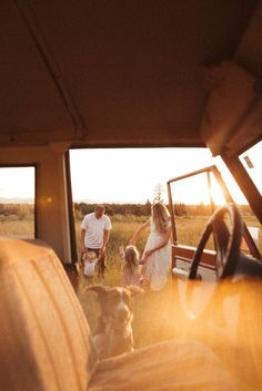 the family is riding in the truck with their dog on the back seat as the sun goes down