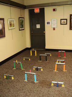 an empty room with several different colored posts in the floor and pictures on the wall