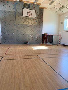 an indoor basketball court with hard wood flooring and climbing wall in the back ground