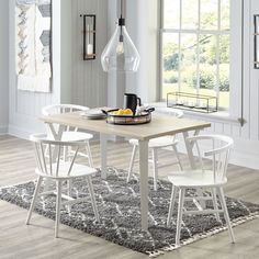 a dining room table with white chairs and a bowl of fruit on the top of it