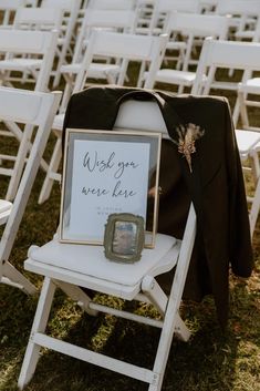 a chair with a sign on it sitting in front of rows of white folding chairs