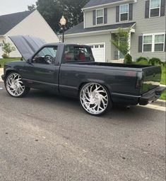 a black truck with chrome rims parked in front of a house