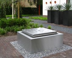 a large metal box sitting on top of a brick walkway next to trees and bushes