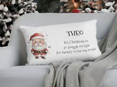 a christmas pillow sitting on top of a white chair next to a tree with lights