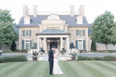 a bride and groom standing in front of a large house