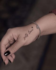 a woman's hand with a small tattoo on the wrist that says self love