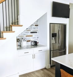 a kitchen with white cabinets, stainless steel appliances and a tv mounted on the wall