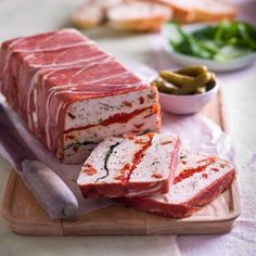 slices of meat on a cutting board with pickles and bread in the background