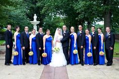 a group of people standing next to each other in front of a fountain and trees