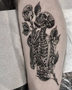 a black and white photo of a skeleton with roses on it's thigh, holding a knife