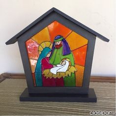 a stained glass nativity scene is displayed on a wooden stand with a black base