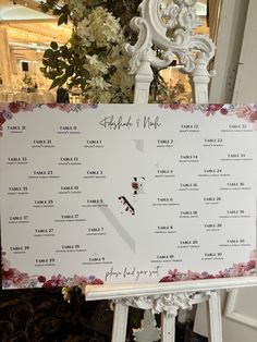 a wedding seating chart is displayed on a easel in front of a floral arrangement