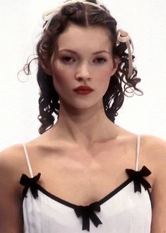 a woman in a white dress with black bows on her head and hair pulled back