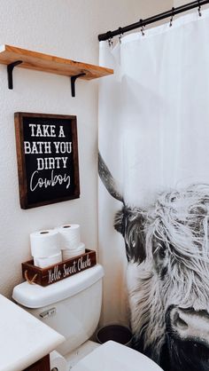 a bathroom with a cow shower curtain and toilet paper roll holder on the wall next to it