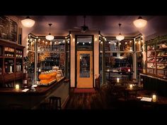 the inside of a restaurant with many tables and stools in front of windows that have lights on them