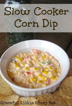 a white bowl filled with corn dip surrounded by tortilla chips