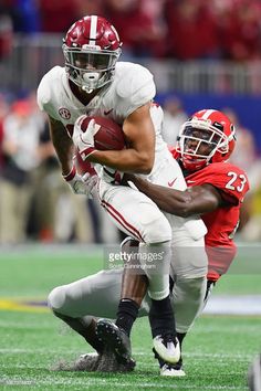 a football player running with the ball in front of an opposing player on a field