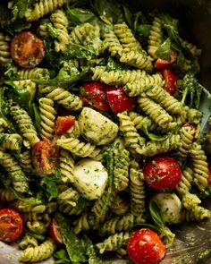 pasta salad with spinach and tomatoes in a bowl