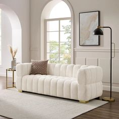 a living room with a white couch and rugs on the wooden floor next to a large window