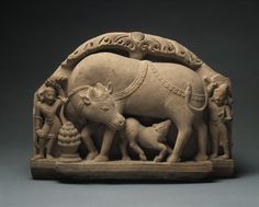 an animal sculpture with people around it on a gray background in the shape of a cow