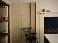 a chair sitting in front of a fire place next to a shelf filled with wood