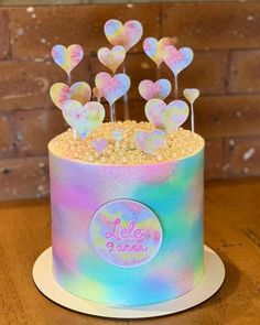 a holographic cake decorated with heart shaped lollipops and marshmallows