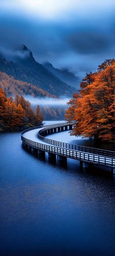 a long bridge over a body of water with trees on both sides and mountains in the background