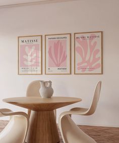 a dining room table and chairs with posters on the wall above it, along with two vases