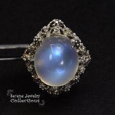 This large rare Moonstone Cabochon Ring is set in 14k solid gold and exhibits mesmerizing blue flash aduralescence. Scintillating diamonds surround this natural beauty! Ring Size: 5.75 Total Weight: 13.65 grams Precious Metal: 14k solid gold Precious stones: -Moonstone Center Stone: 18.5mm x 16.2mm, 23.05 carats -White Round Diamond: 0.4ct Gold Ring Vintage, Moonstone Cabochon, Platinum Diamond Rings, Purple Sapphire, Cabochon Ring, Shiny Things, Platinum Ring, 14k Gold Ring, Vintage Ring