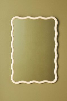 a mirror that is on the wall with a light green background and white trim around it