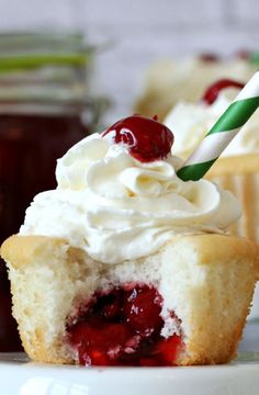 a close up of a cupcake with whipped cream and cherries on the top