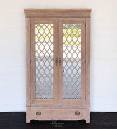 an old wooden cabinet with glass doors on the front and back sides, against a white wall