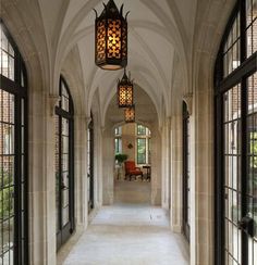 an arched hallway with two lamps hanging from it's ceiling and windows on both sides