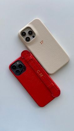 two cell phones sitting next to each other on top of a white table with red cases