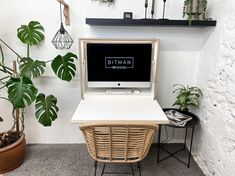 a white desk topped with a computer next to a potted plant