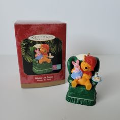 a toy winnie the pooh and piglet sitting on a chair next to a box