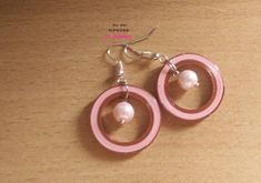 two pink hoops with pearls are hanging from the end of each earring on a wooden surface