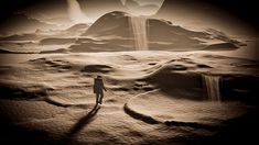 a man standing on top of a desert covered in snow next to a giant rock