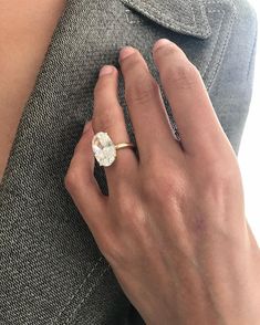 a woman's hand wearing a gold ring with a white flower on the side