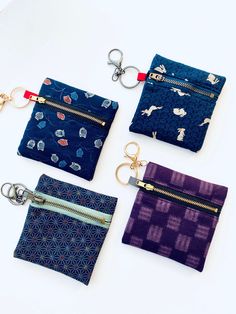 four small zippered pouches with keychains on them, all in different patterns