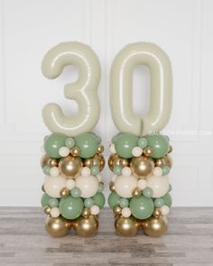 the number 30 balloon is made out of gold, green and white balloons on top of each other