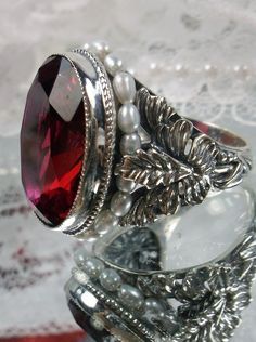 Ruby Red Art Nouveau style sterling silver ring, oval ruby red gem with seed pearls encircling the gem edge and palm tree silver filigree accents on each side of the band Handmade Elegant Ruby Ring, Elegant Handmade Ruby Ring, Antique Silver Ruby Promise Ring, Heirloom Silver Garnet Jewelry, Antique Silver Garnet Jewelry, Victorian Style Silver Ruby Ring Hallmarked, Victorian Sterling Silver Ruby Ring For Formal Occasions, Heirloom Silver Ruby Ring With Polished Finish, Formal Silver Ruby Ring With Engraving