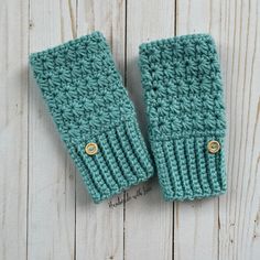 two green knitted mittens sitting on top of a wooden table