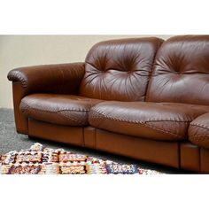 a brown leather couch sitting on top of a rug