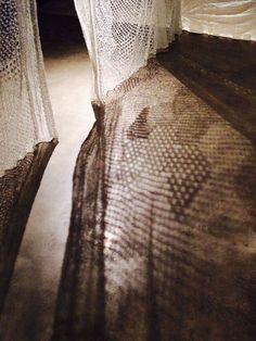 shadows cast on the floor in front of sheer curtained bedspreads and curtains