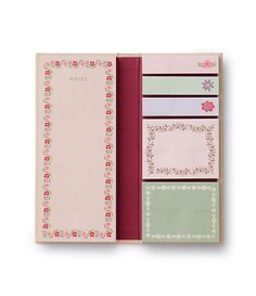 an open notebook with pink and green flowers on it, sitting in front of a white background